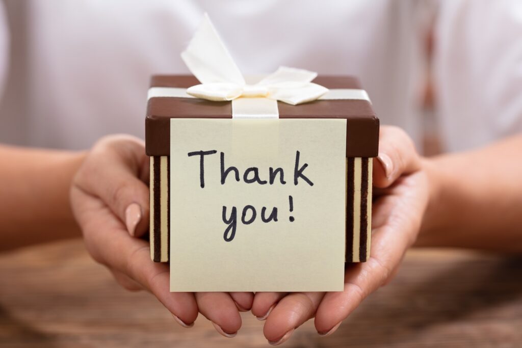 Close-up Of Thank You Adhesive Note On Gift Box Over The Desk