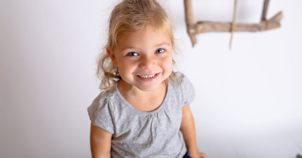 A young girl smiles in a nursery photograph